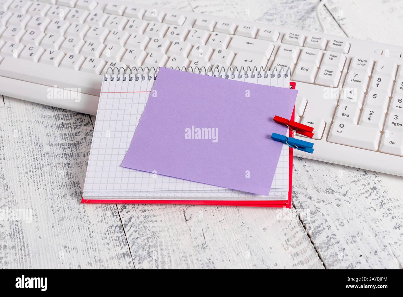 Bloc-notes en papier carré avec une note vide en forme de rectangle ci-dessus épinglée par deux clous de giropage sur la feuille. Clavier blanc sous a c Banque D'Images