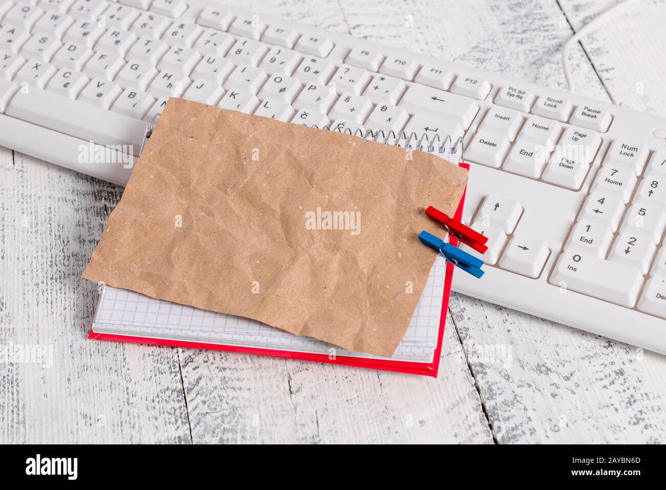 Bloc-notes en papier carré avec une note vide en forme de rectangle ci-dessus épinglée par deux clous de giropage sur la feuille. Clavier blanc sous a c Banque D'Images