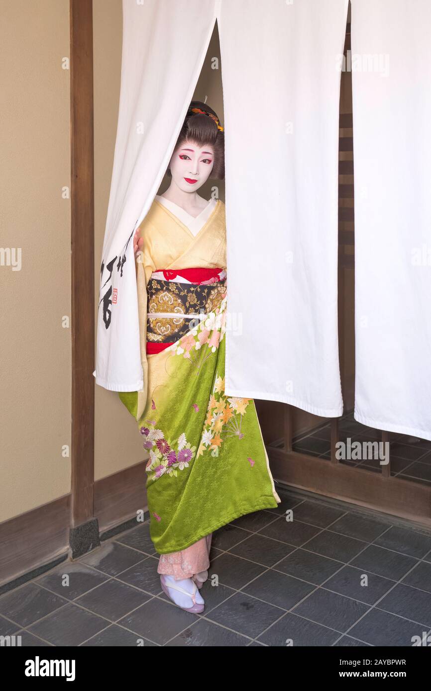 Un Kyoto Geiko regardant à travers un Noren Banque D'Images