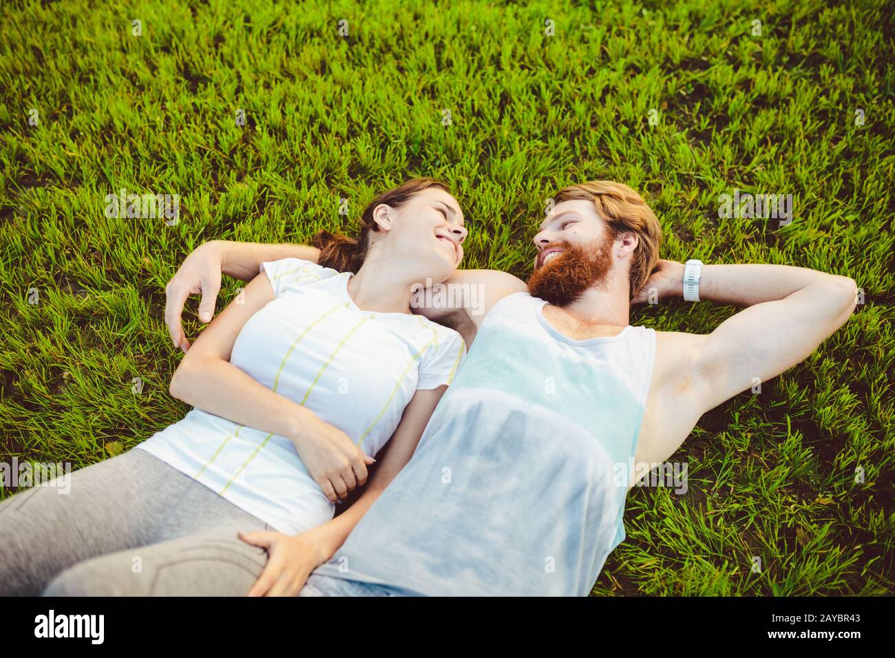 Le thème est le sport et un style de vie sain. Un jeune homme et un couple de femmes reposent sur leur dos sur l'herbe verte, une pelouse Banque D'Images
