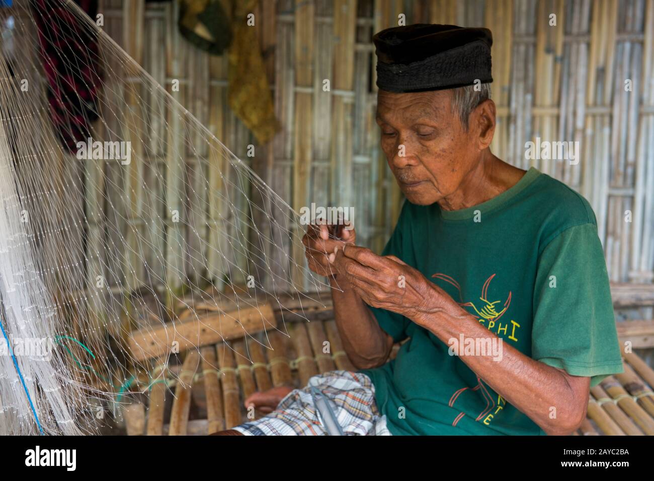 Une scène de village avec un homme local faisant un filet de pêche dans le village bojau Sea Gypsy sur l'île de Bungin, célèbre pour vivre dans des maisons stilt au-dessus de l'eau Banque D'Images
