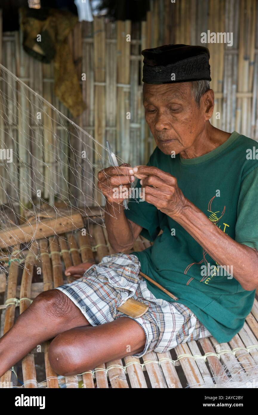 Une scène de village avec un homme local faisant un filet de pêche dans le village bojau Sea Gypsy sur l'île de Bungin, célèbre pour vivre dans des maisons stilt au-dessus de l'eau Banque D'Images