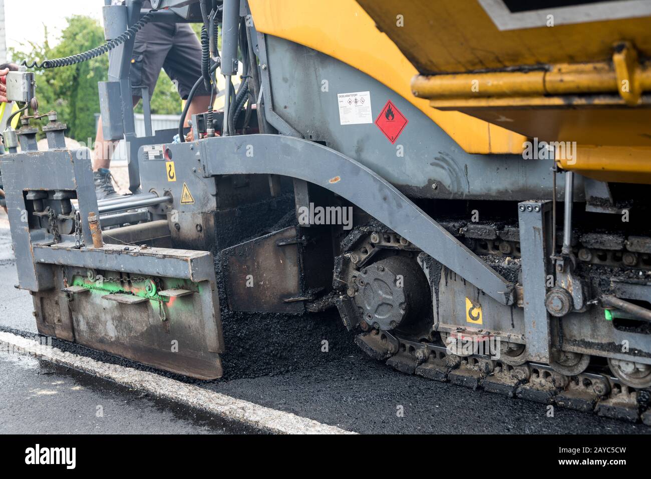 Travailleur de la construction avec machine de construction à asphaltage des travaux - clôture Banque D'Images