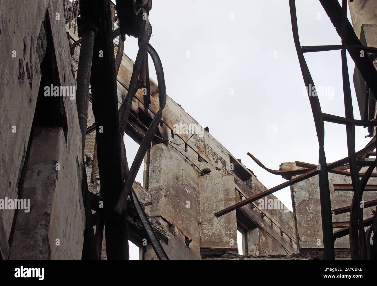 l'intérieur d'un bâtiment industriel détruit avec des murs qui s'effondrent et des poutres tordues et un toit tombé ouvert au ciel Banque D'Images