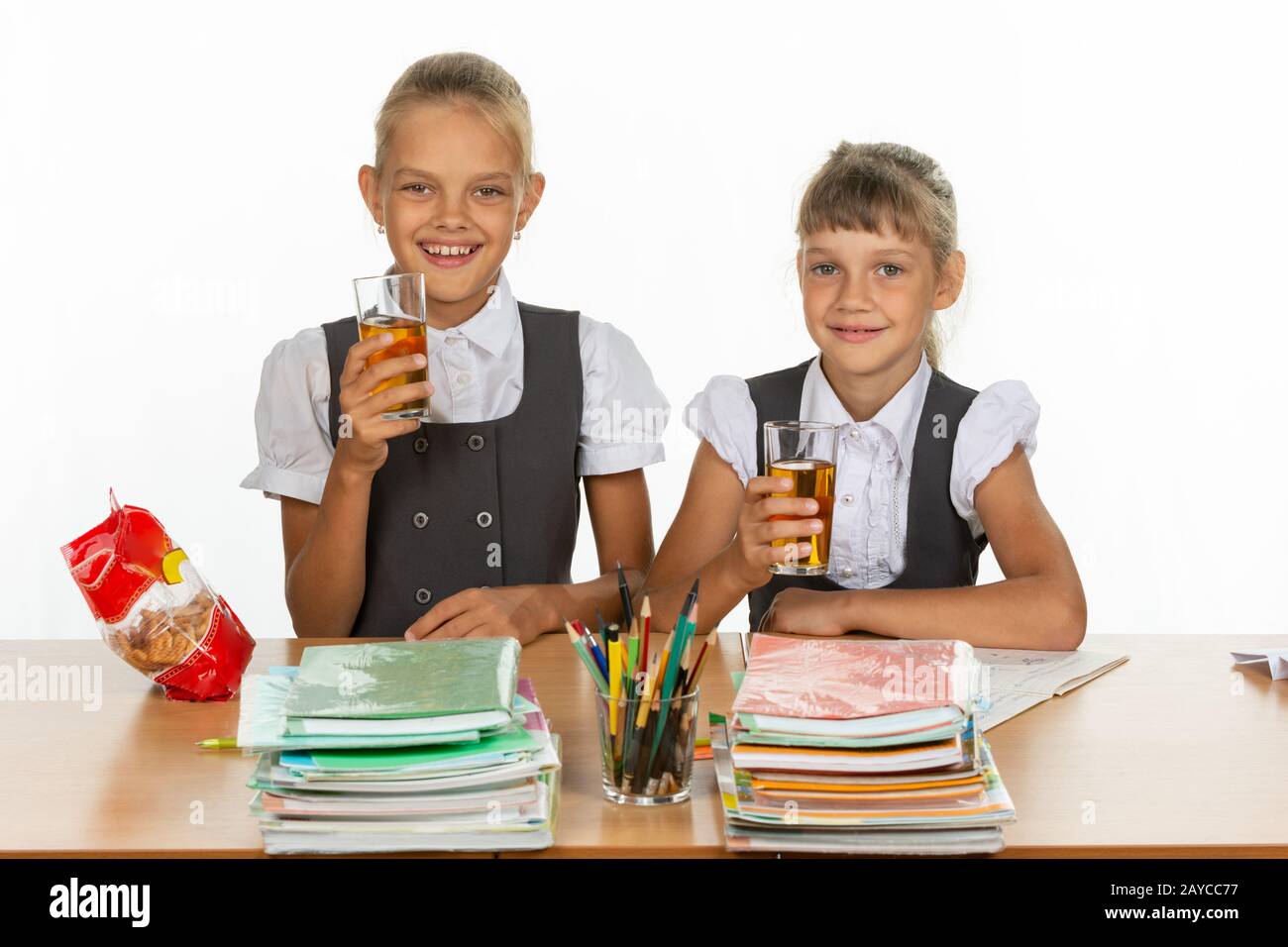 Deux écolières drôle à une table, boire du jus, et regardez dans le cadre Banque D'Images