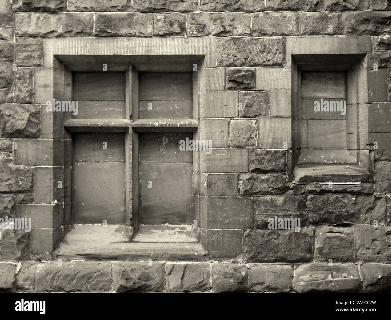 image sépia monochrome d'anciens cadres de fenêtres en pierre bloqués dans un mur rugueux Banque D'Images