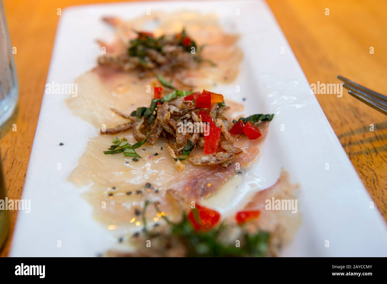 Carpaccio (hamachi brut, émincé de fines tranches, recouvert de chaux, de basilic, d'huile de chaudron et d'échalotes croustillantes) au restaurant Ama à Hanalei, à l'extrémité nord Banque D'Images