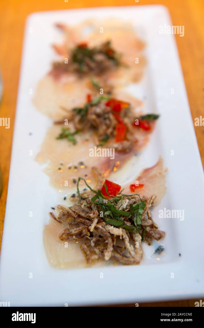 Carpaccio (hamachi brut, émincé de fines tranches, recouvert de chaux, de basilic, d'huile de chaudron et d'échalotes croustillantes) au restaurant Ama à Hanalei, à l'extrémité nord Banque D'Images