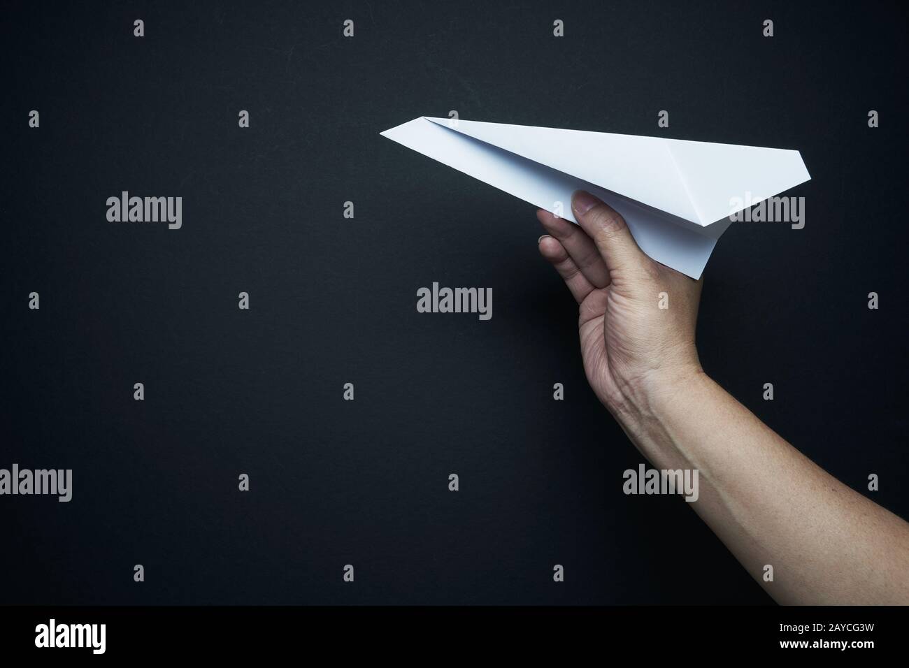 Main tenant avion papier sur fond noir Banque D'Images