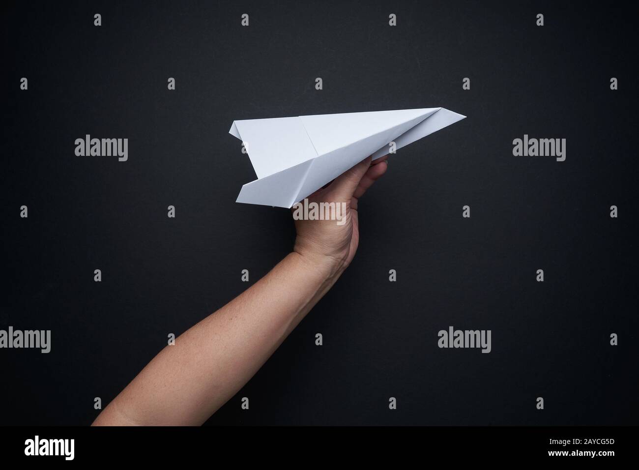 Main tenant avion papier sur fond noir Banque D'Images
