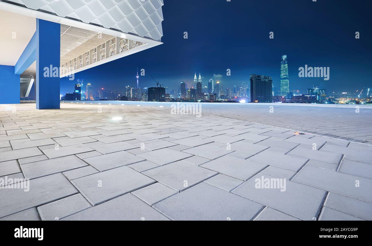 Vue sur le sol vide avec l'extérieur moderne du bâtiment et les gratte-ciel de paysage urbain . Scène de nuit . Banque D'Images