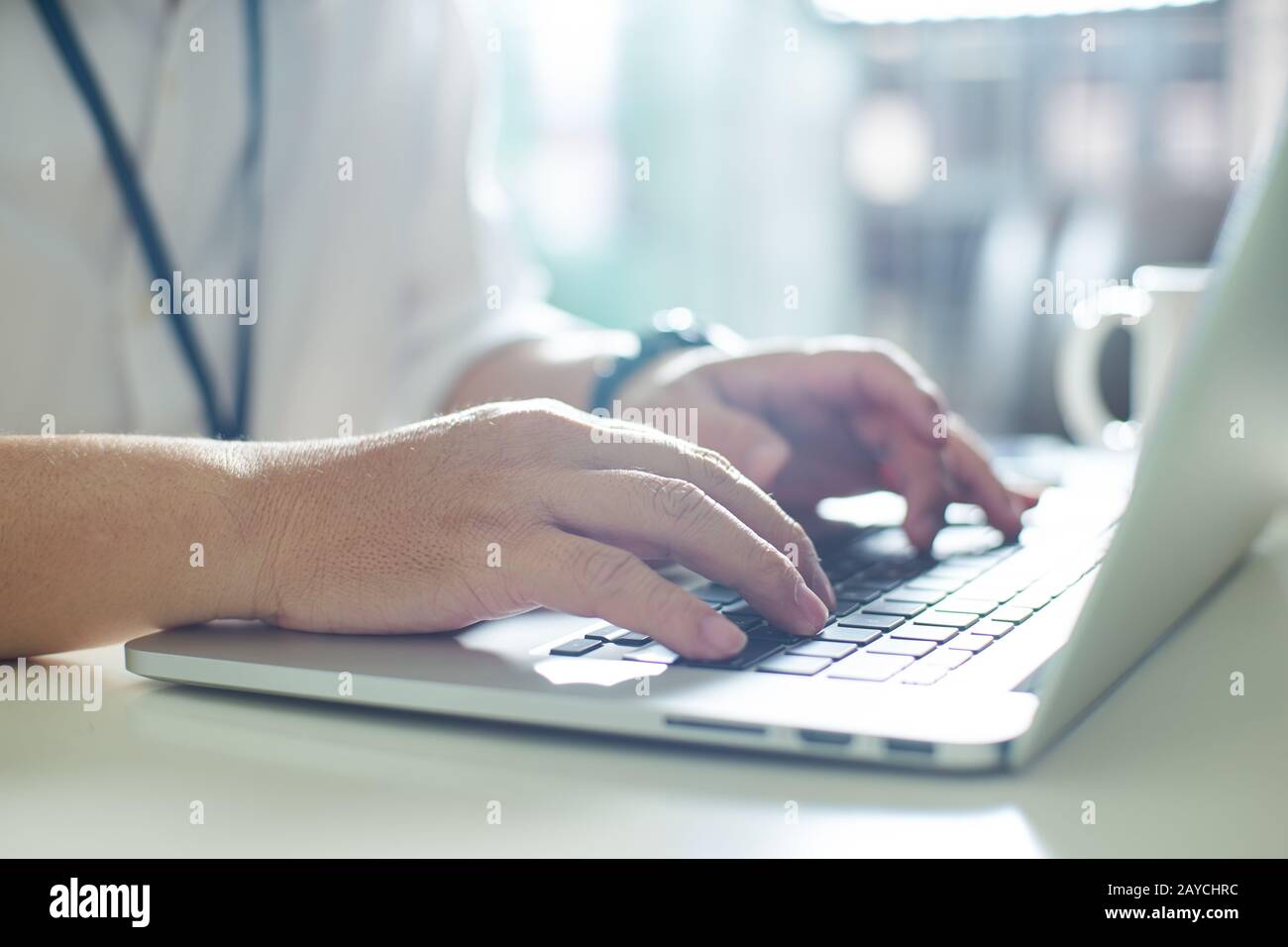 Homme d'affaires utilisant un ordinateur portable avec une tablette et un stylo sur une table blanche au bureau avec une tasse de café Banque D'Images