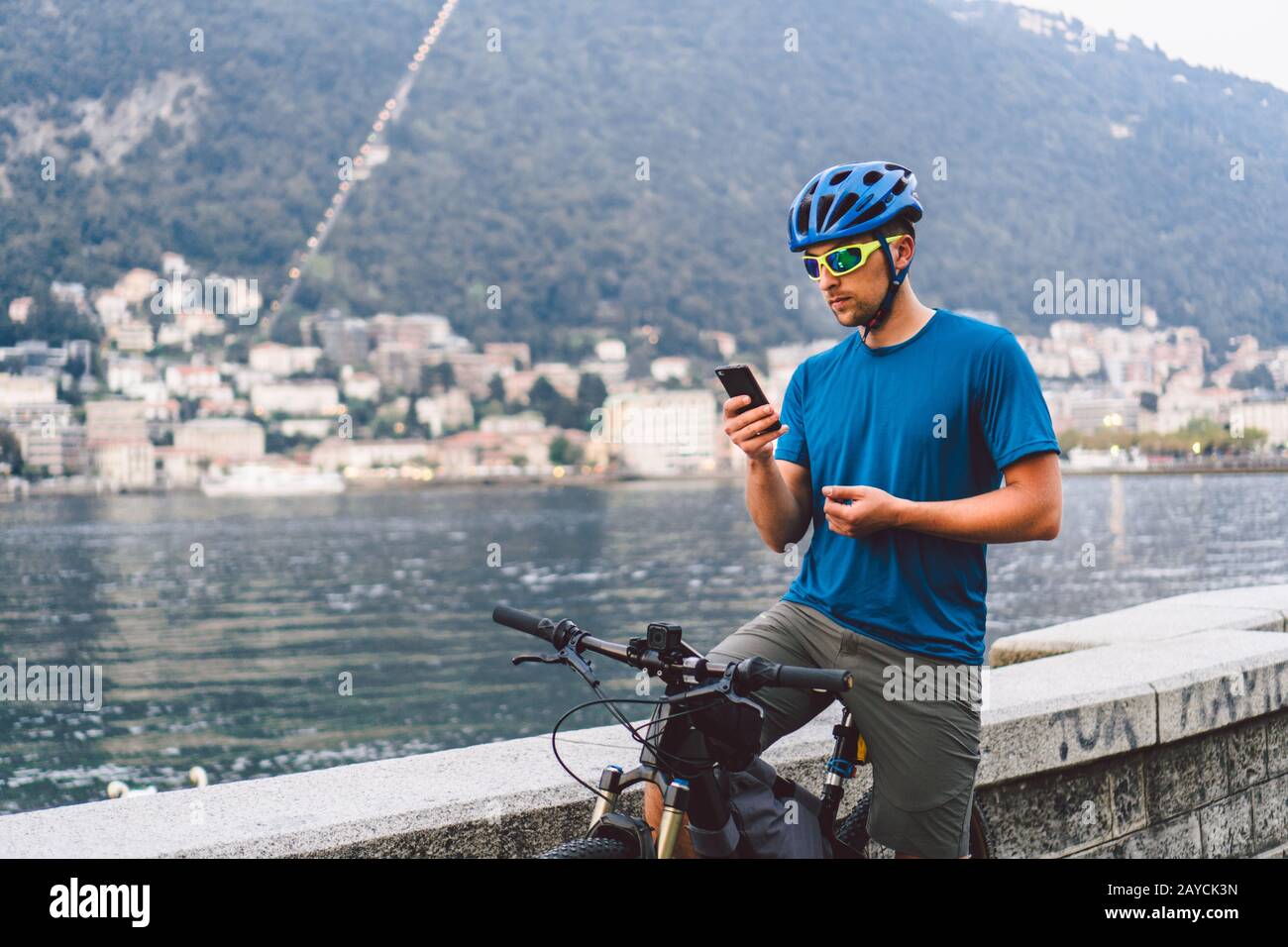 Le thème du tourisme et des voyages en Italie. Un cycliste masculin utilise un téléphone sur la rive du lac de Côme. Un homme de tourisme dans un casque avec un Banque D'Images