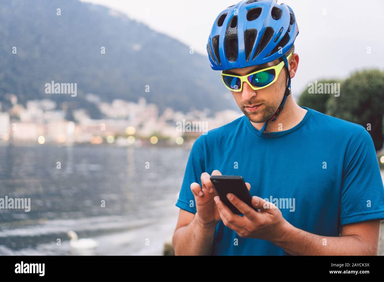 Le thème du tourisme et des voyages en Italie. Un cycliste masculin utilise un téléphone sur la rive du lac de Côme. Un homme de tourisme dans un casque avec un Banque D'Images