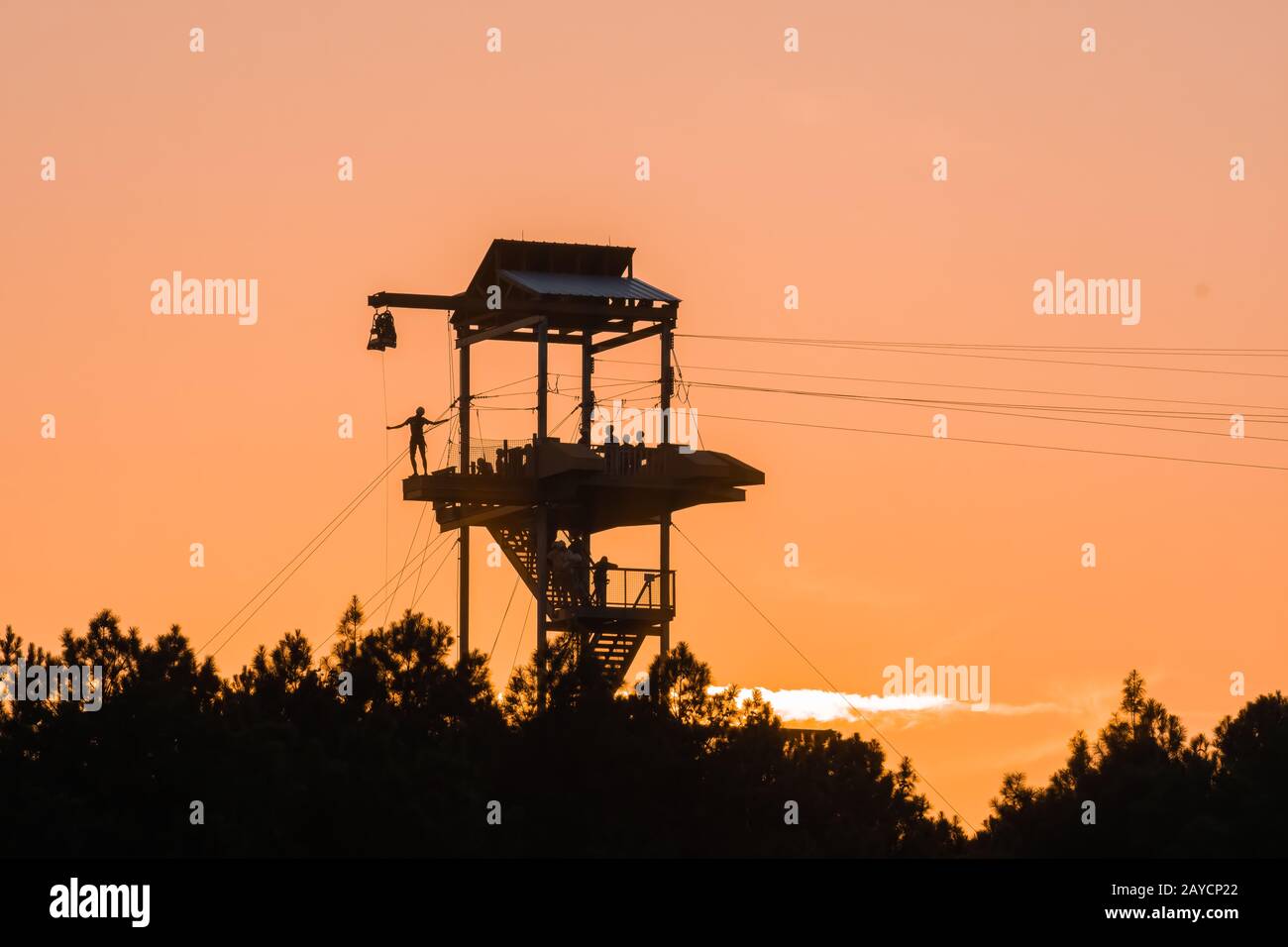 tour de tyrolienne avec silhouettes de personnes au coucher du soleil Banque D'Images