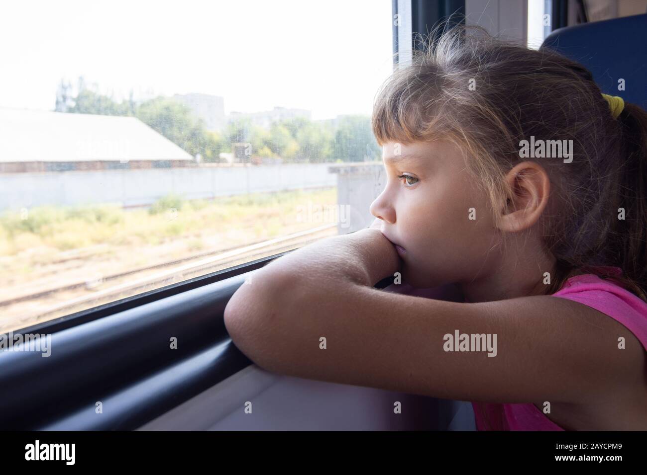 Une fille de huit ans regarde par la fenêtre dans un train électrique Banque D'Images