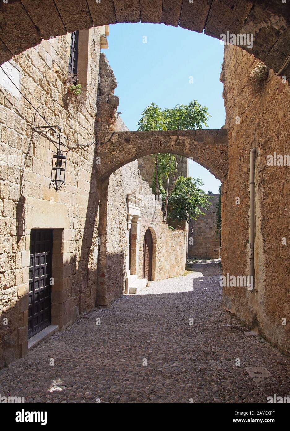 une rue pavée médiévale calme de la ville de rhodes avec de vieux bâtiments et des arches entre des bâtiments en pierre Banque D'Images