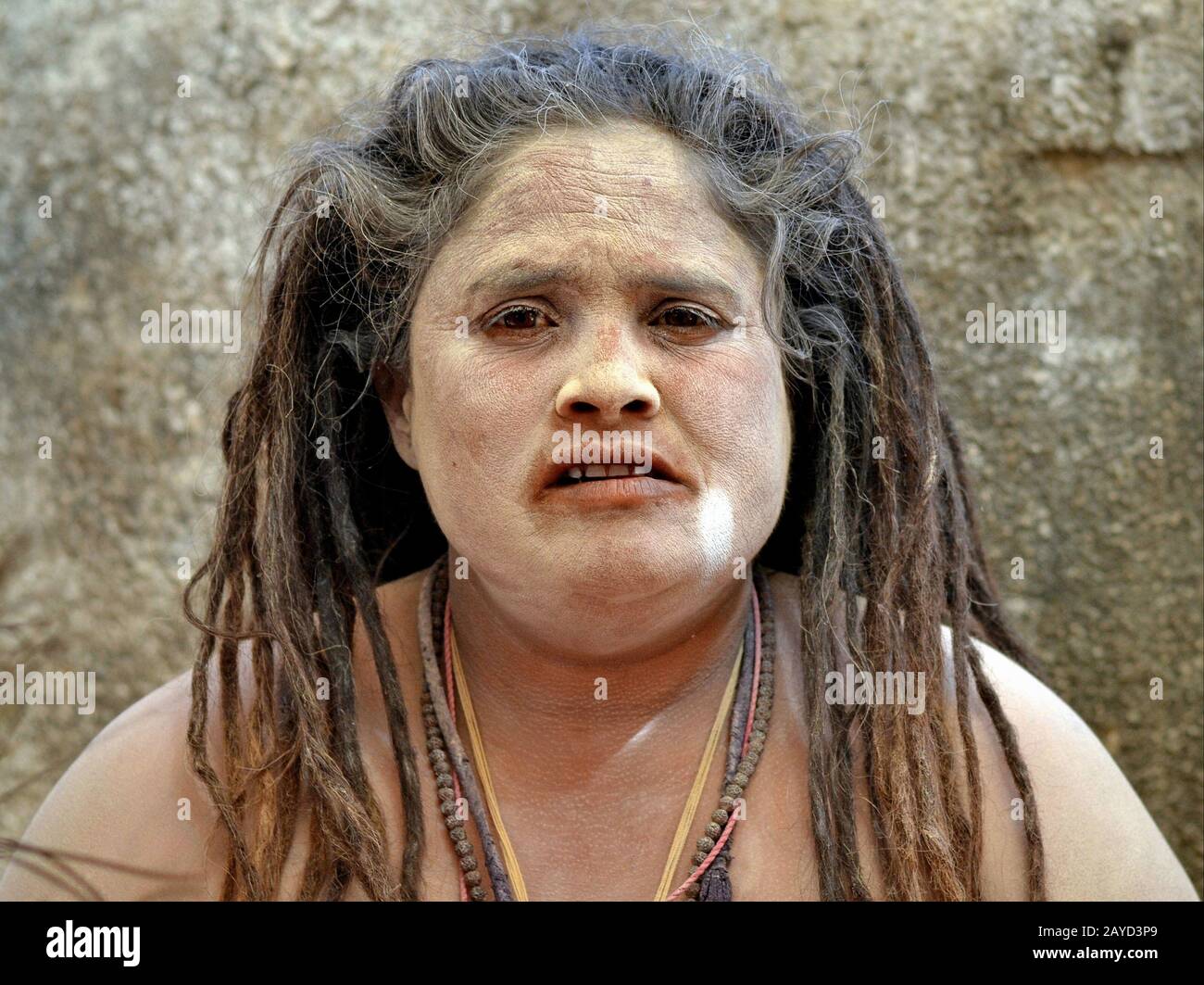 Chubby indienne hindou femelle sadhu (sadhvi) avec de longs dreadlocks et cendres sacrées (vibhuti) sur son visage et les épaules pose pour la caméra. Banque D'Images