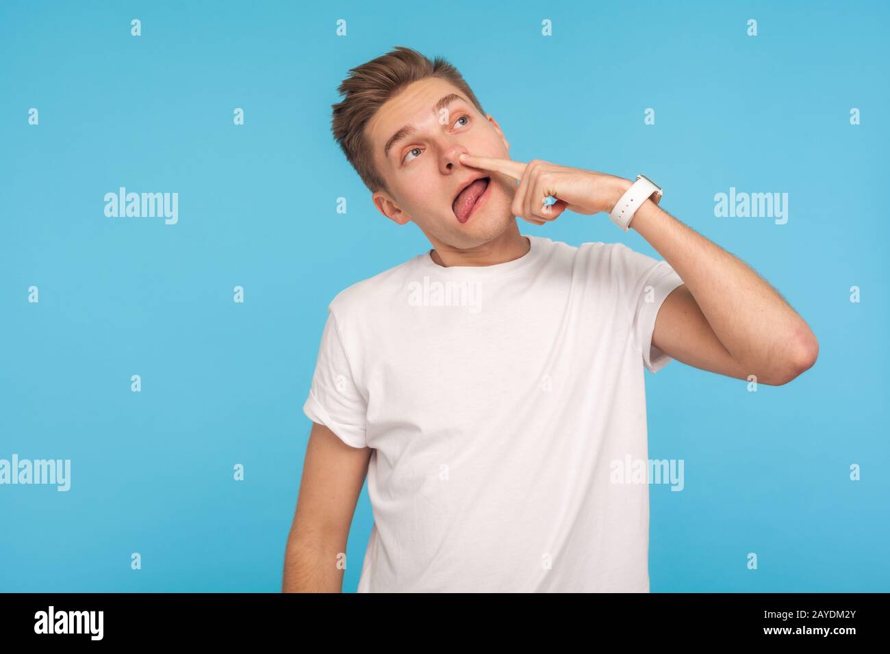 Mauvaise habitude. Portrait d'un homme insensé non cultivé dans un t-shirt blanc décontracté tirant sur les boosers, piquant le nez sale avec une drôle d'expression drôle stupide. I Banque D'Images