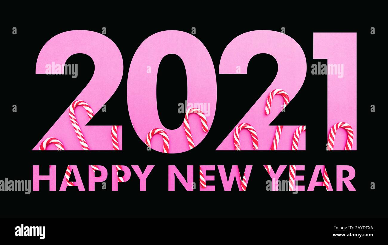2021 la veille du nouvel an. Le papier noir a coupé la couche numéro 2021 contre les bonbons de Noël sur fond rose. Bonne année, texte, modèle de carte de vœux Banque D'Images