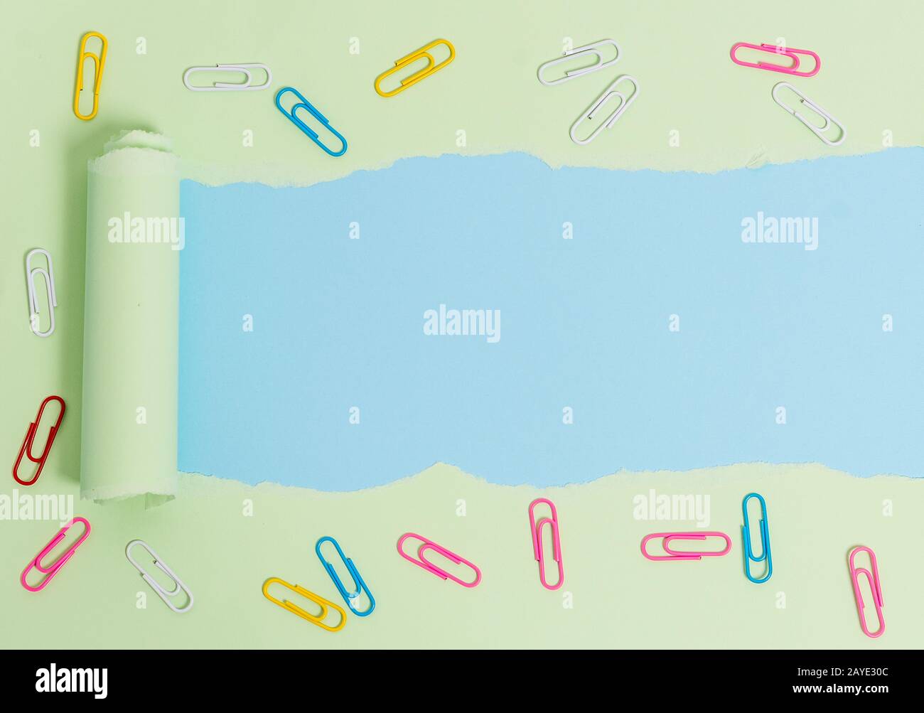 Carton déchiré avec clip en papier placé au-dessus d'une table de couleurs douces. Papier épais déchiré et fixe sur fond pastel ordinaire. A Banque D'Images