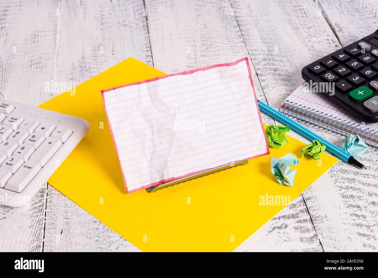 Notepaper en couleur blanche se tenant sur un fil tampon entre un clavier et un livre de mathématiques. L'ancien papier de notation se trouve près de l'ordinateur Banque D'Images