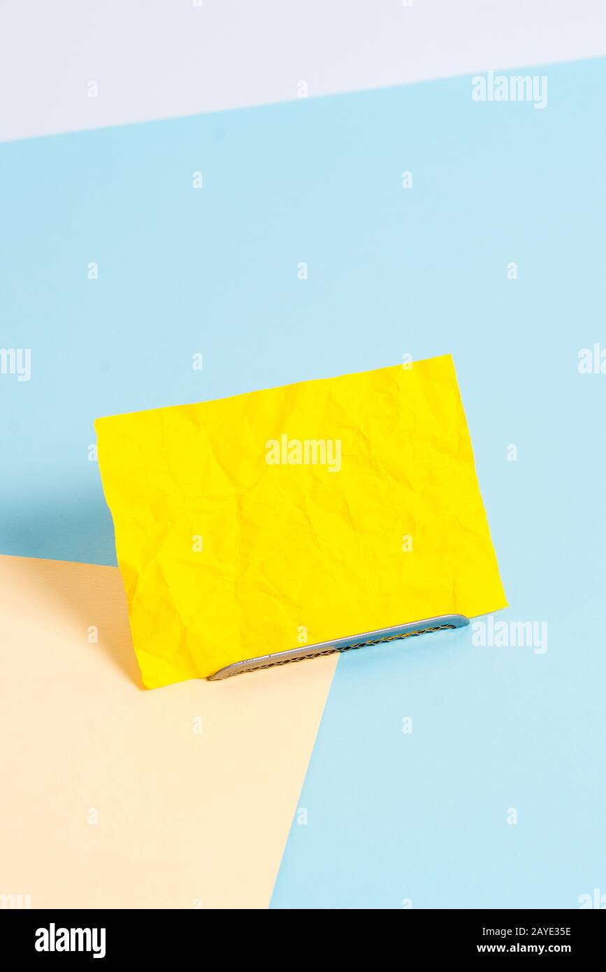 Feuille de papier inclinée sur un fil tampon avec un fond pastel doux. Notepaper sur le bord de la table vide pleine de plusieurs couleurs Banque D'Images