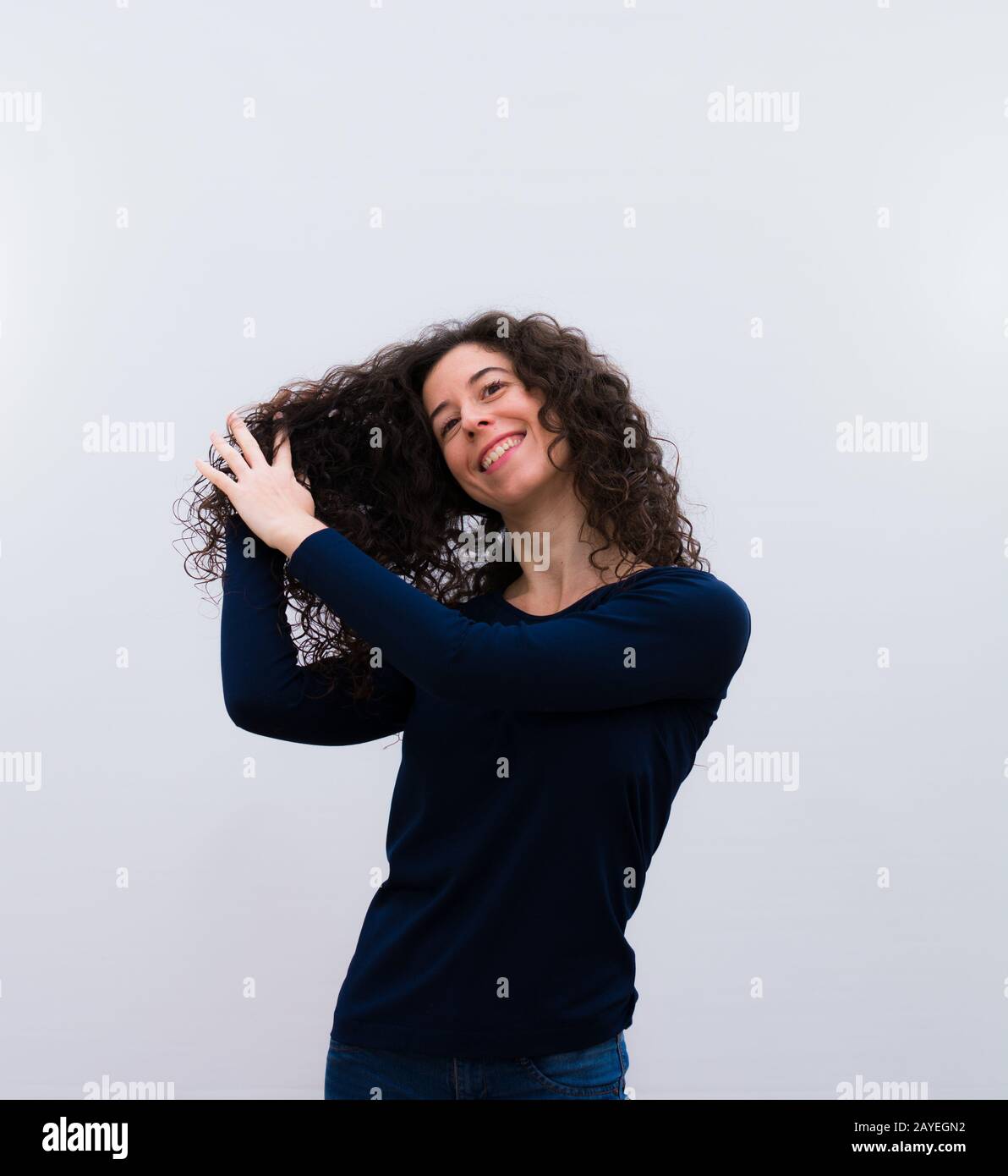 Jeune jolie femme avec des cheveux noirs et frisés montrant ses cheveux frisés Banque D'Images