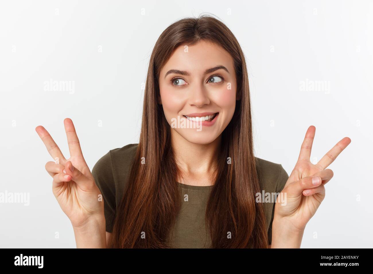 Jeune femme montrant deux doigts, positif ou geste de paix, sur fond blanc. Banque D'Images