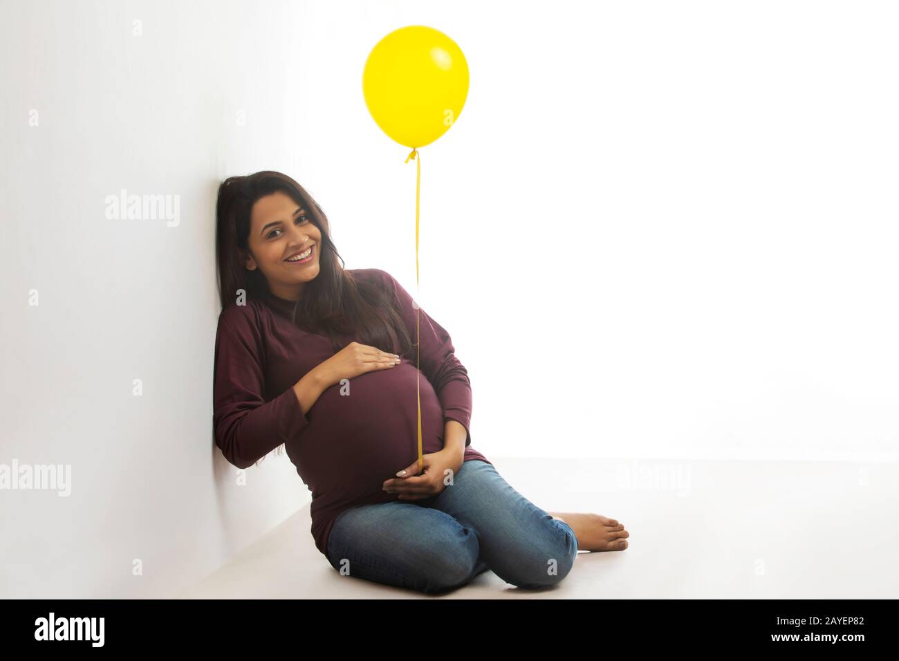 Femme enceinte tenant un ballon et souriant à son bébé bosse. Banque D'Images