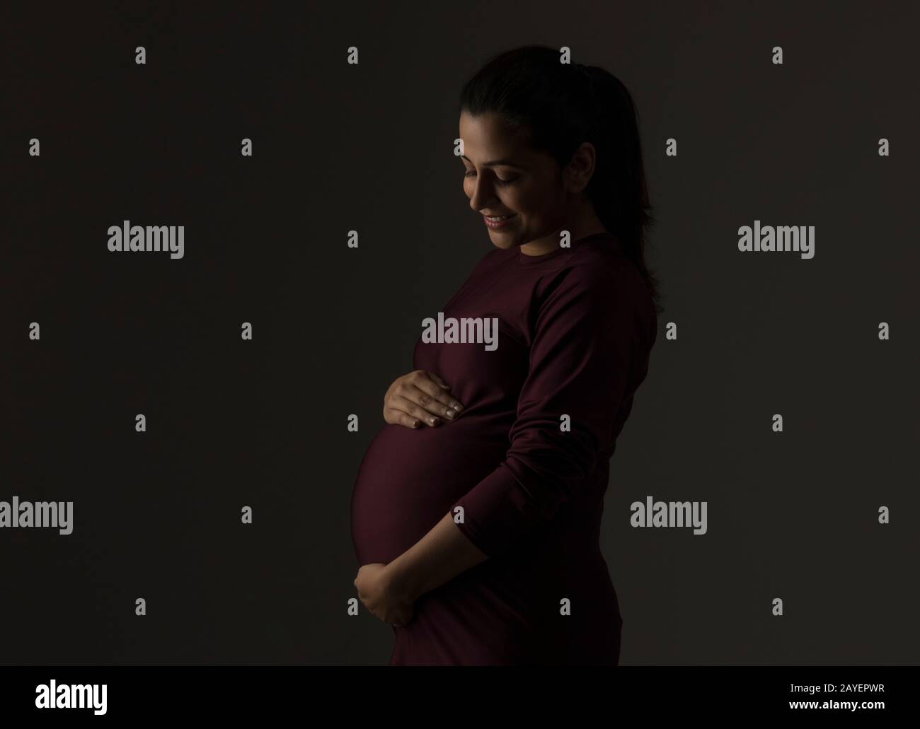 Femme enceinte souriant avec ses mains sur son bébé bosse. Banque D'Images