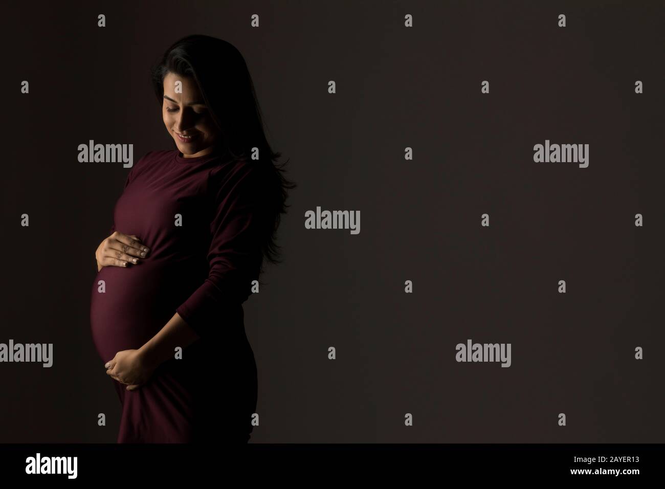 Femme enceinte tenant son bébé bosse en anticipation. Banque D'Images