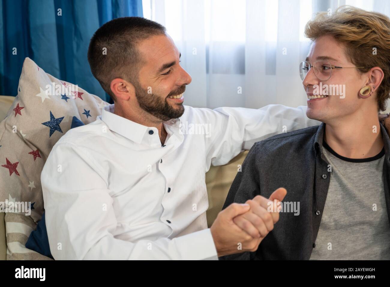 Stock photo d'un couple gay de jeunes garçons assis sur un canapé tenant les mains Banque D'Images