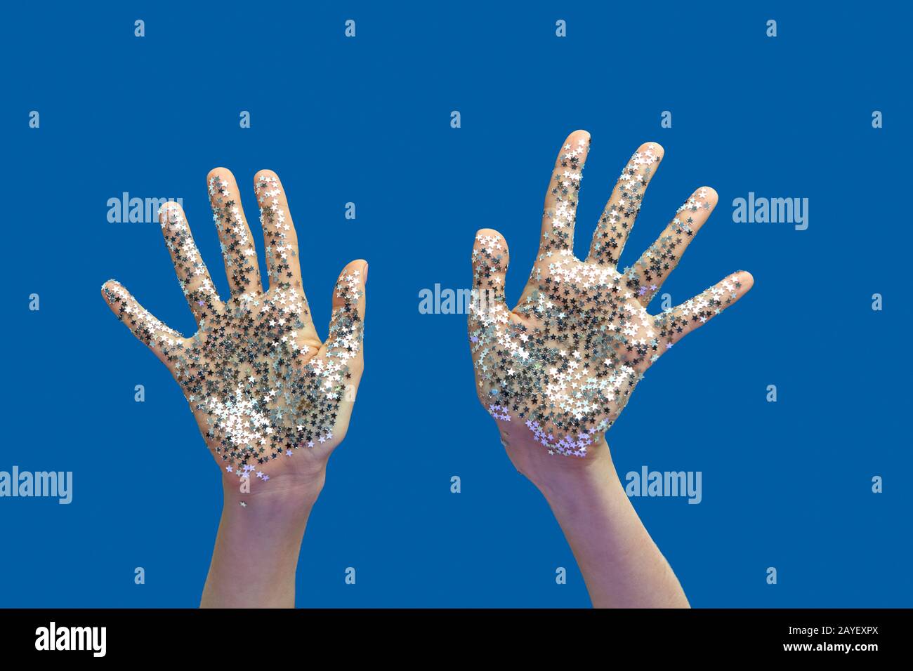 Les mains d'une femme avec la décoration de vacances glitter de petites étoiles sur un bleu. Banque D'Images