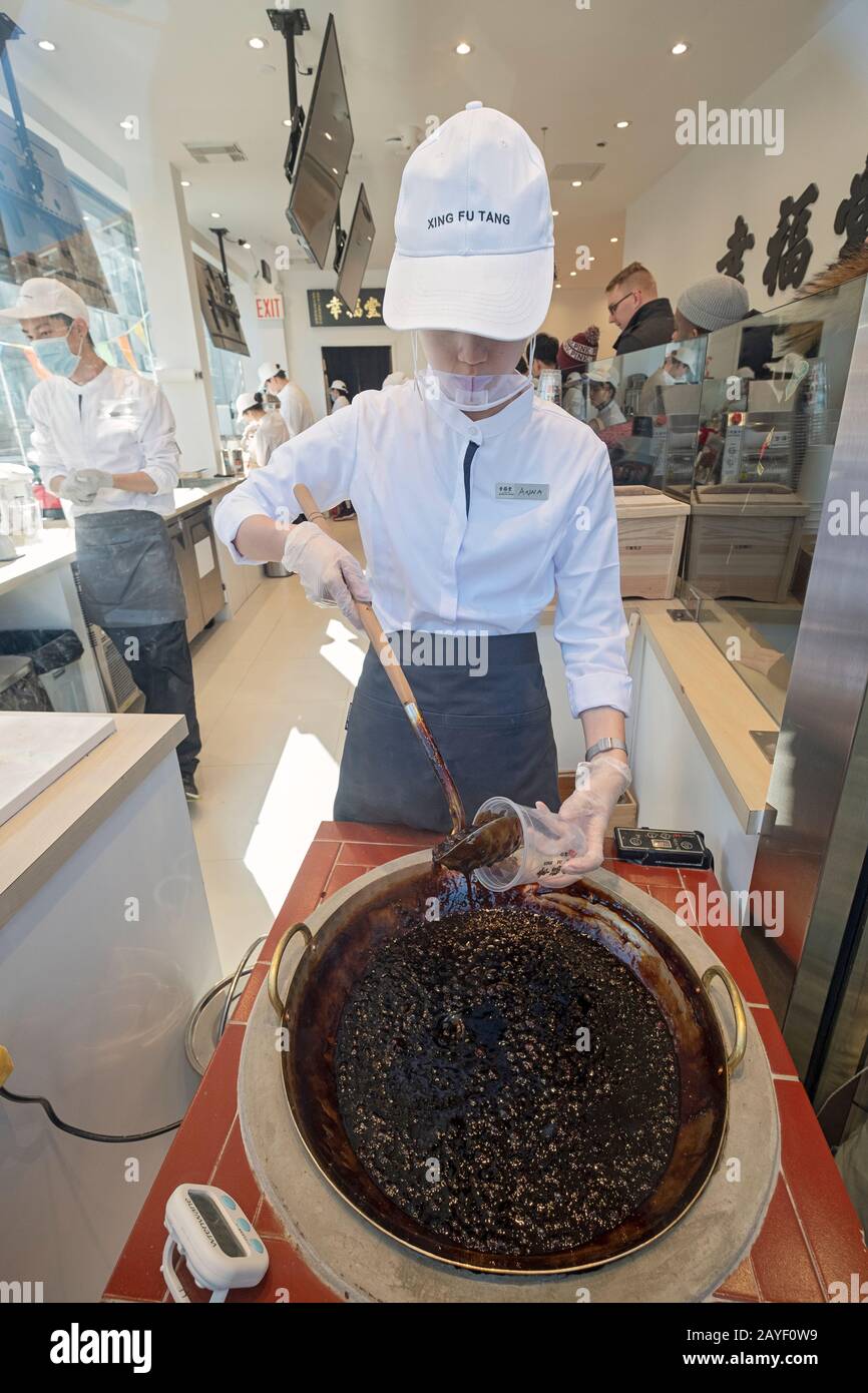 Un jeune américain asiatique prend un verre de lait boba dans la fenêtre de Xing Fu Tang, un magasin taïwanais sur Main St. à Flushing, Queens, quartier chinois de New York. Banque D'Images