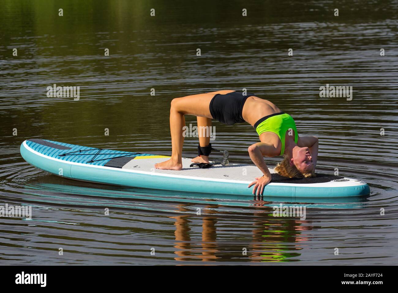 Femme en pont pose sur SUP à l'eau Banque D'Images