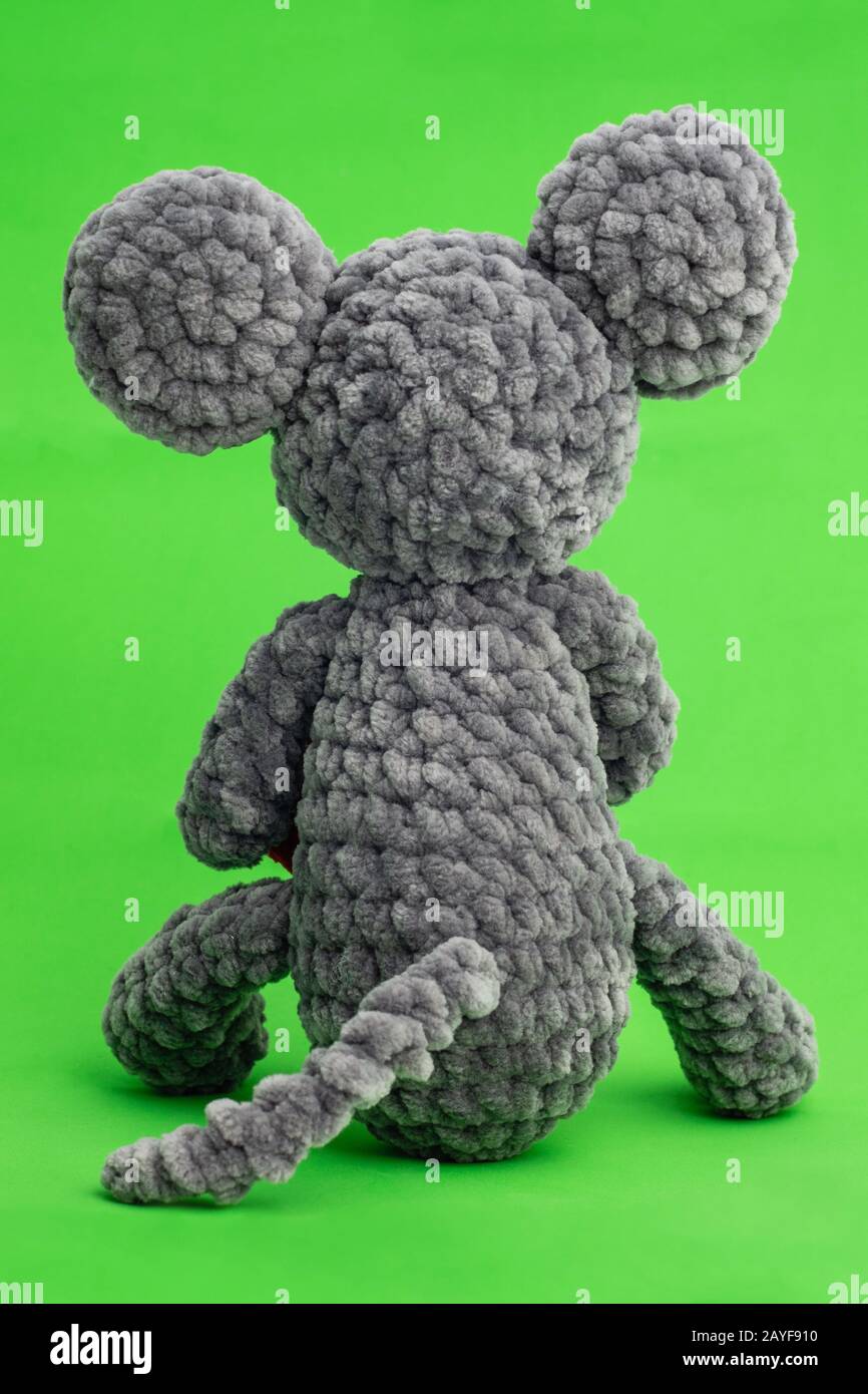 Tricoté gris souris avec un cœur dans la main sur un fond vert, vue arrière Banque D'Images