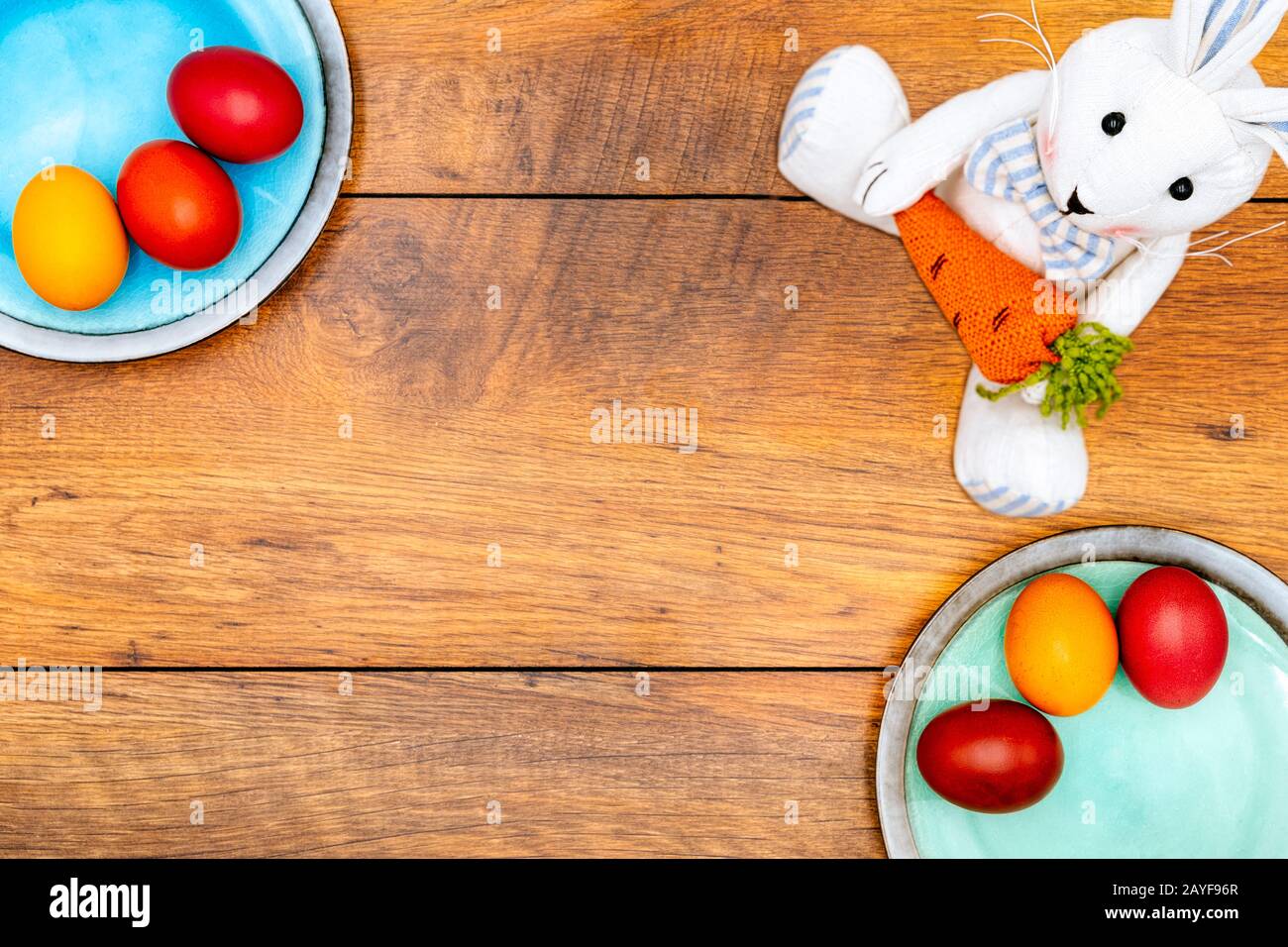 Six œufs de Pâques colorés sur deux assiettes et un lapin de Pâques avec fond en bois Banque D'Images