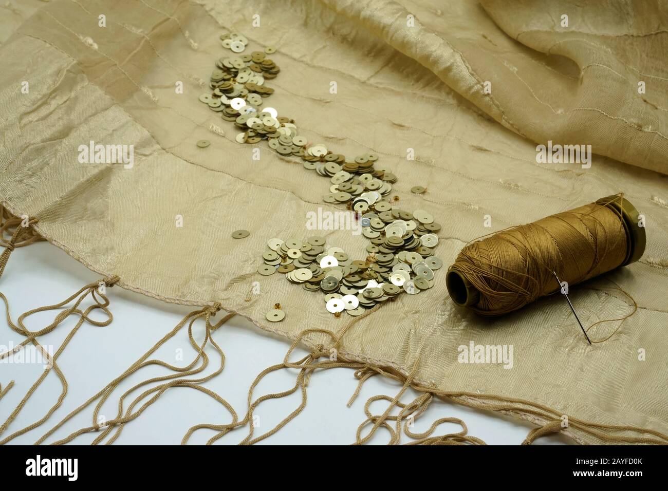 Séquines d'or, spool de fil d'or, aiguille sur fond de soie d'or déchiré. Accessoires de couture et de décoration utilisés pour embellissement de robes. Cop Banque D'Images