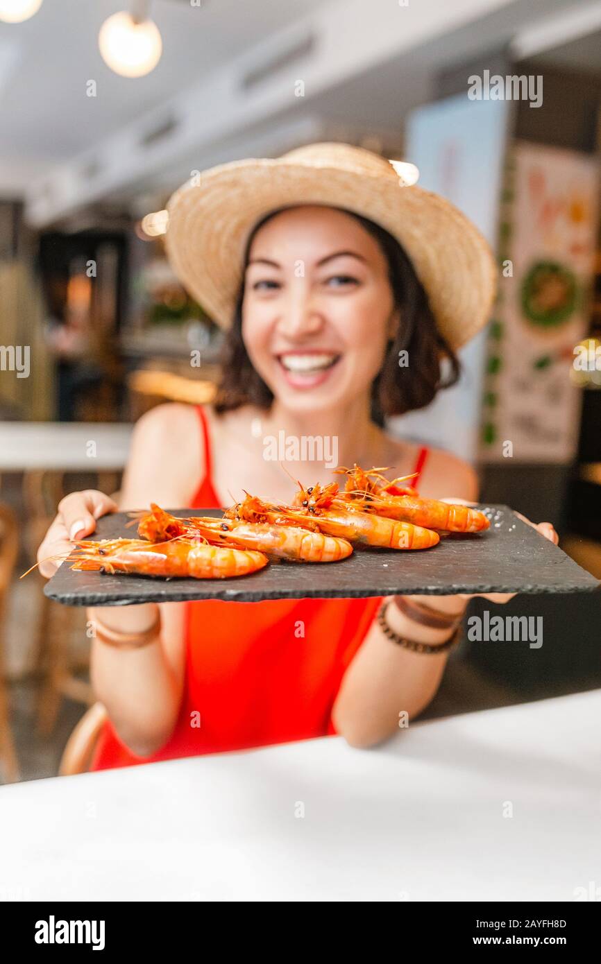 Bonne femme asiatique à chapeau manger de la cuisine locale espagnole grillades de fruits de mer Banque D'Images