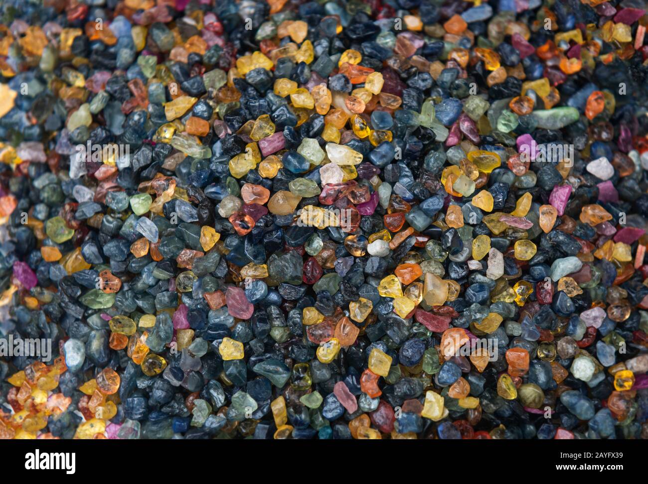 Mélangez des pierres précieuses minérales brutes colorées sur le marché des bijoux avec un éclairage extérieur. Banque D'Images