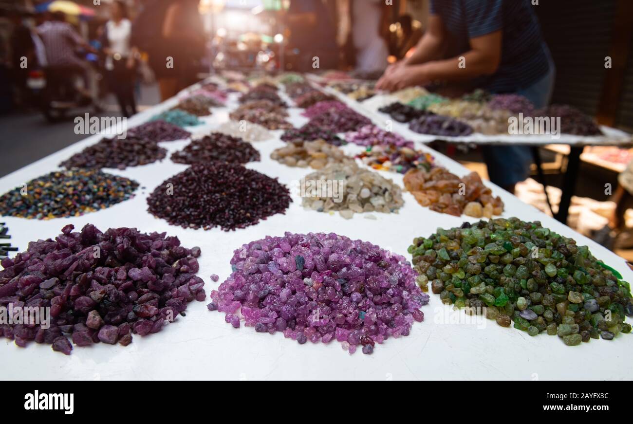 Mélangez le rubis brut coloré et d'autres pierres précieuses minérales sur le marché de la joaillerie avec l'éclairage extérieur. Banque D'Images