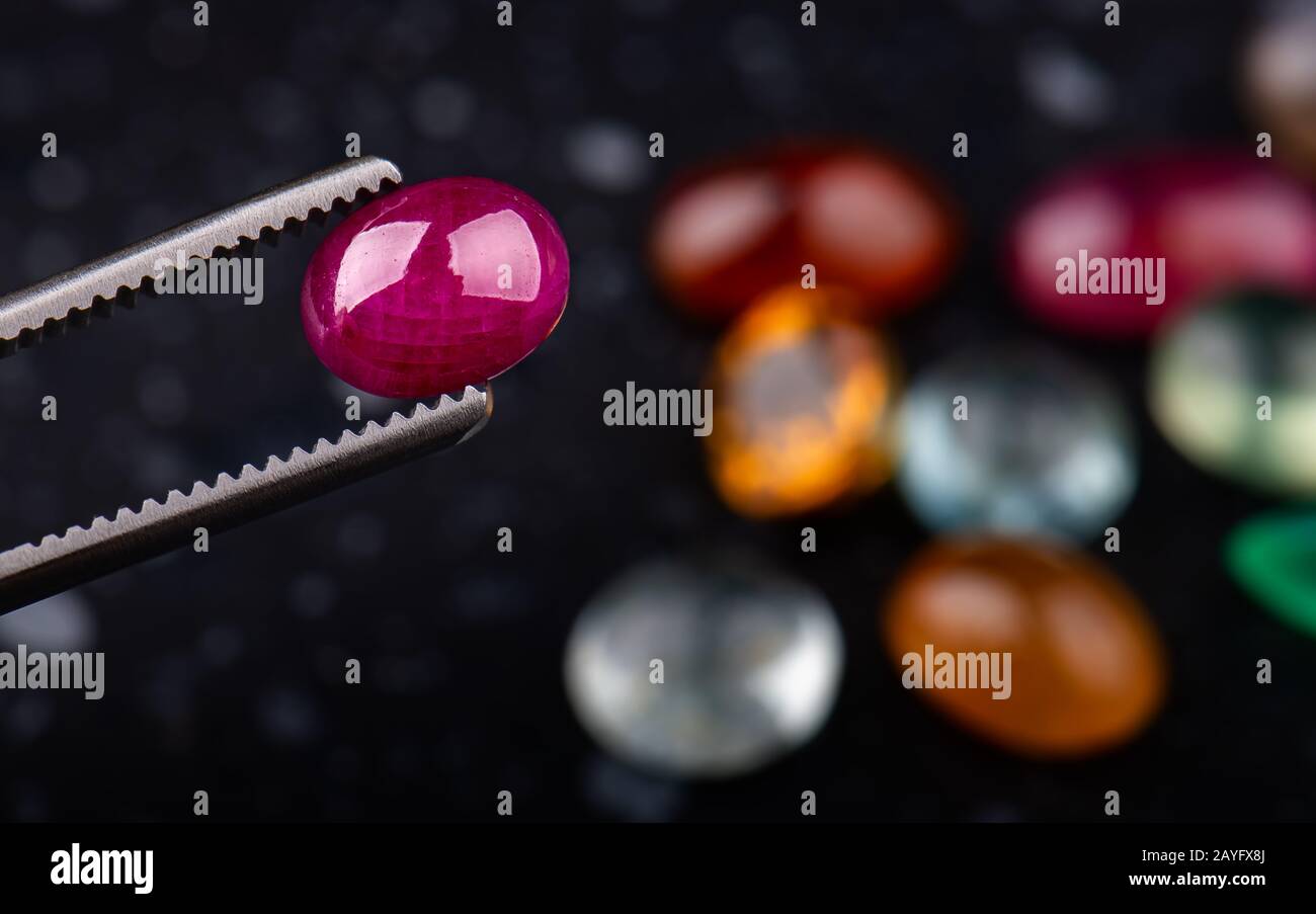 Pierre gemme minérale ruby coupée ronde avec fond de pierres sombres. Banque D'Images