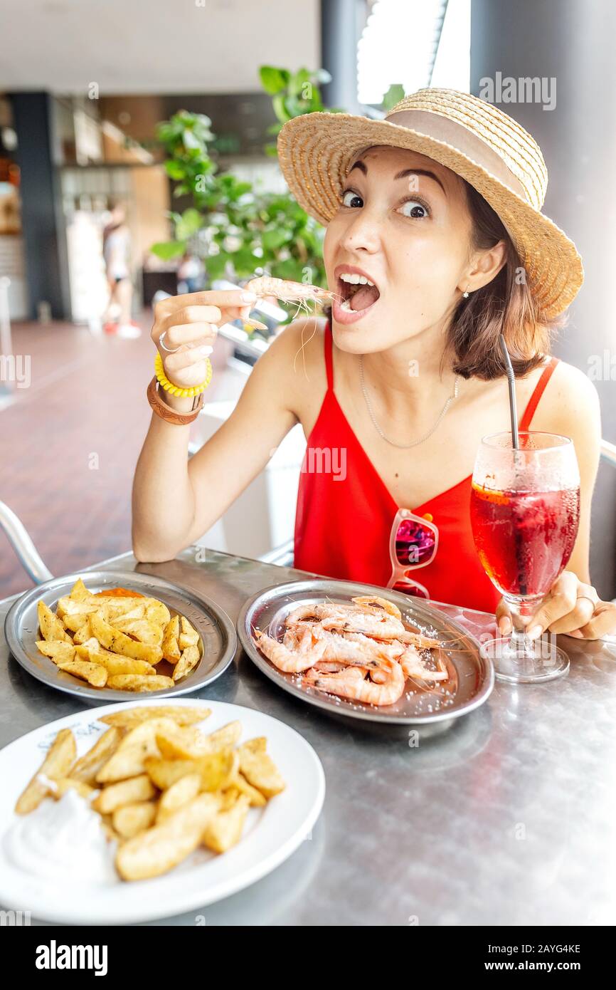 Bonne femme asiatique à chapeau manger de la cuisine espagnole locale fruits de mer grillés et crevettes Banque D'Images