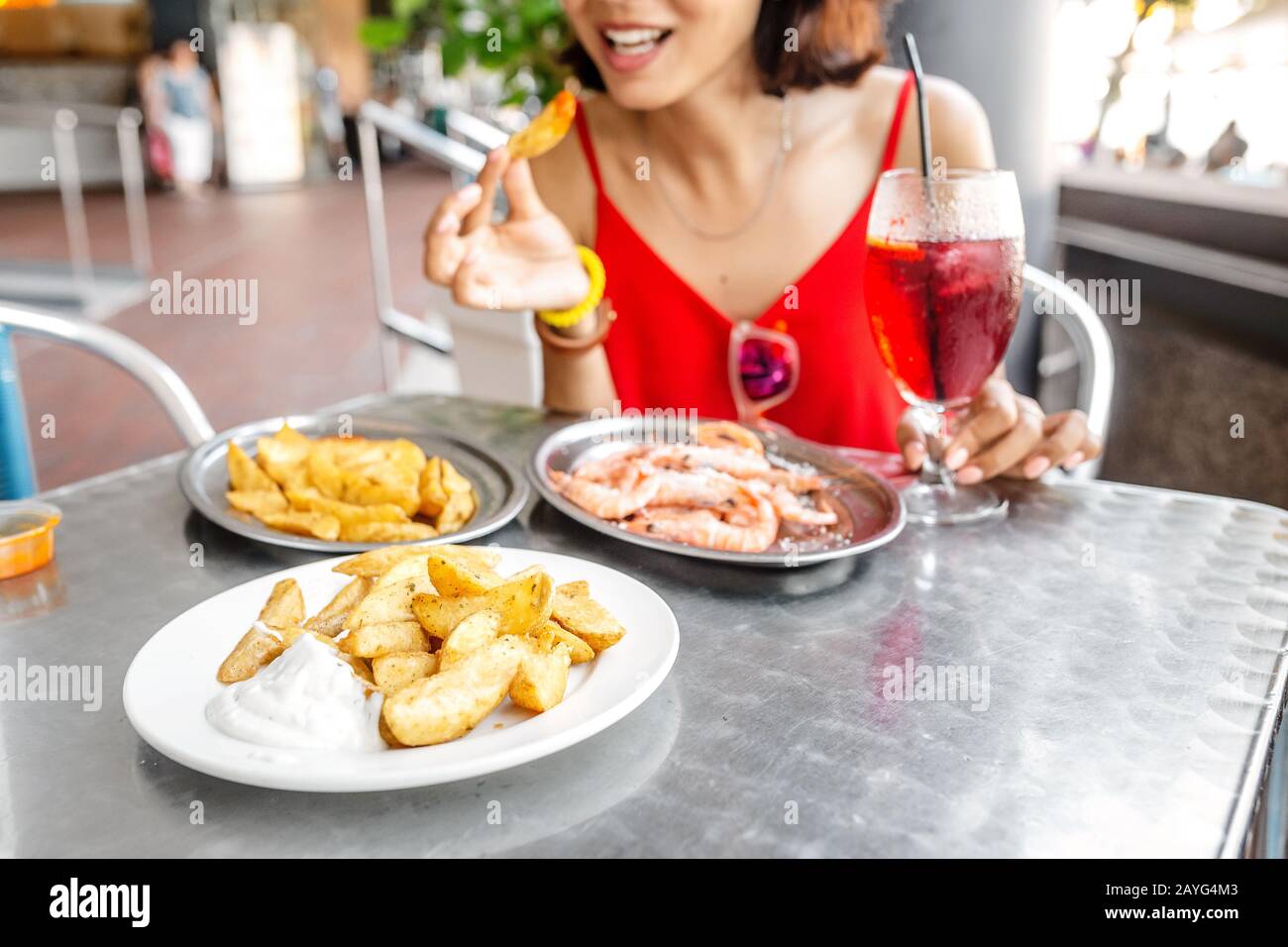 Bonne femme asiatique à chapeau manger de la cuisine espagnole locale fruits de mer grillés et crevettes Banque D'Images