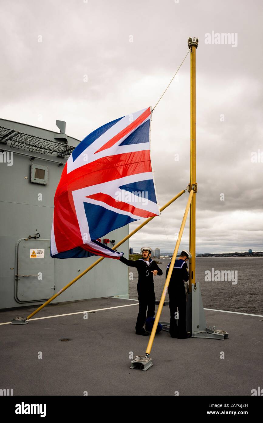 Les marins hissent l'Union Jack monter le personnel du nouveau porte-avions HMS QUEEN ELIZABETH de la Marine royale à l'arrivée à Halifax, en Nouvelle-Écosse. Banque D'Images