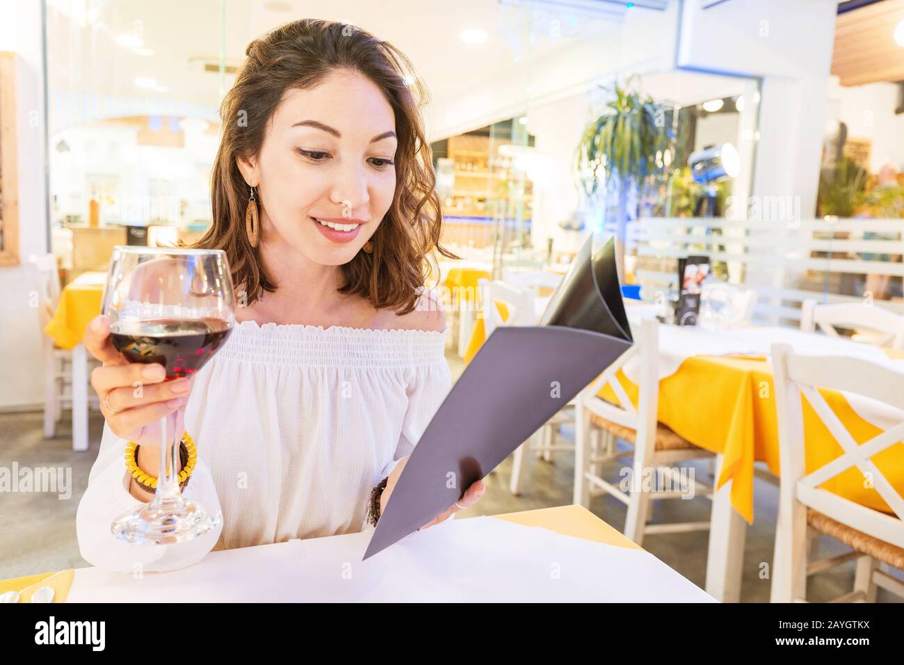 Femme buvant du vin et du menu de lecture au restaurant Banque D'Images