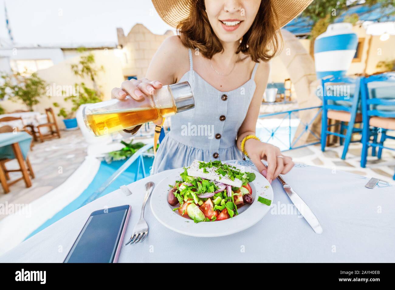 Jeune fille élégante dans le restaurant salade d'assaisonnement à l'huile d'olive. Concept de cuisine grecque et de légumes frais Banque D'Images