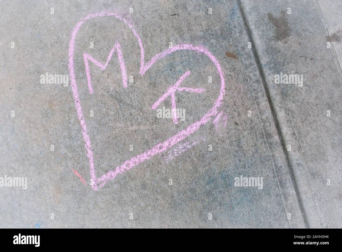Les amoureux ont laissé leurs initiales dans un motif en forme de coeur craché sur le trottoir dans un parc de la ville. Banque D'Images