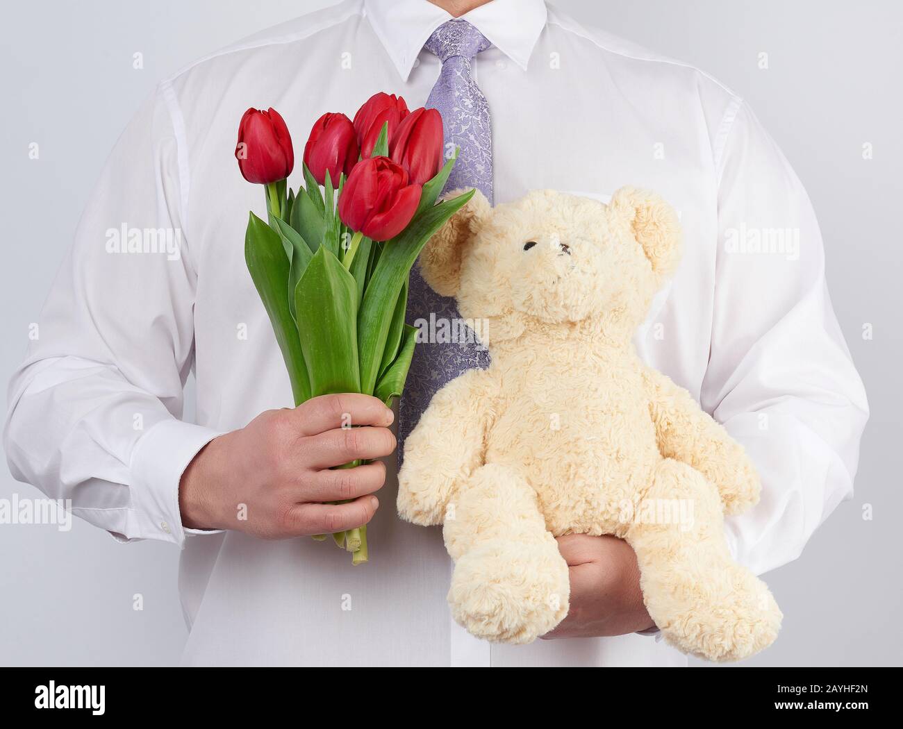 L Homme Adulte Dans Une Chemise Blanche Contient Un Bouquet De Tulipes Fleuris Rouges Et Un Ours Blanc En Peluche Fond Blanc Joyeux Anniversaire Date Concept De Voeux Photo Stock Alamy